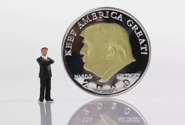 Businessman standing next to a Silver coin with Donald Trump on it