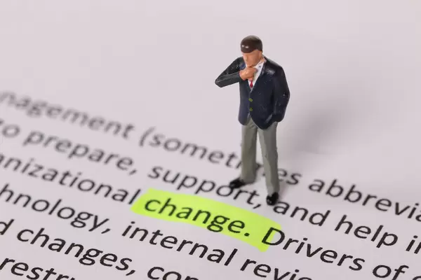 Businessman standing next to a text Change highlighted in yellow
