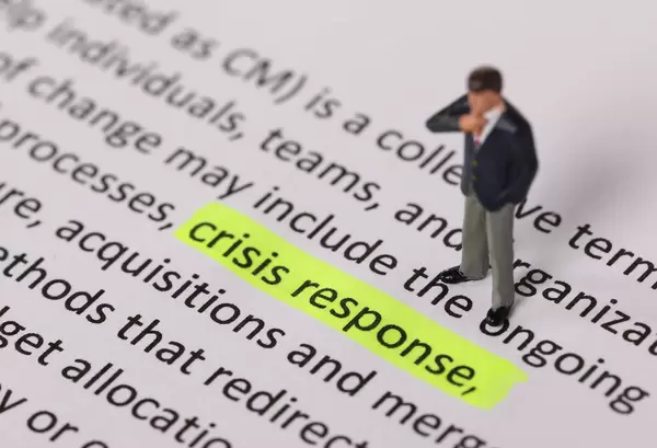 Businessman standing next to a text Crisis Response highlighted in yellow
