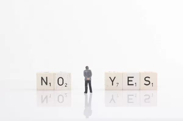 Businessman standing next to yes and no text on wooden blocks