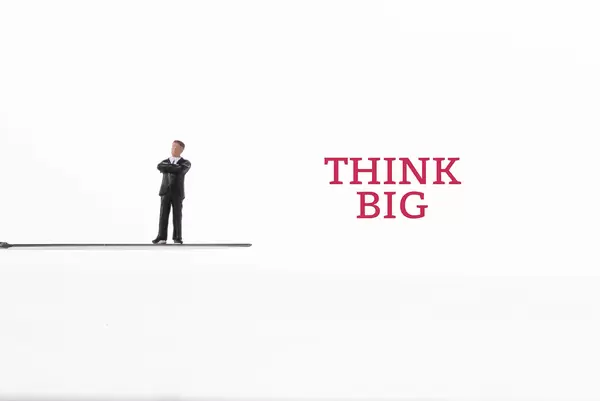 Businessman standing on knife with Think Big text