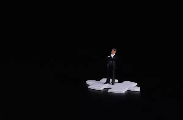 Businessman standing on puzzle piece wtih black background