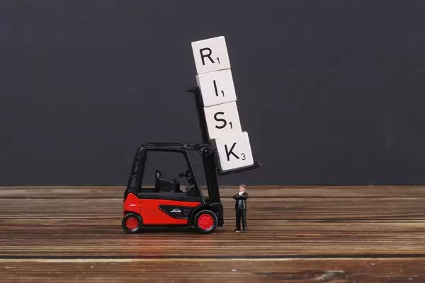 Businessman standing under wooden blocks with risk text