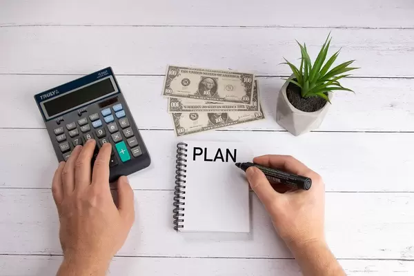 Businessman using calculator and writing plan