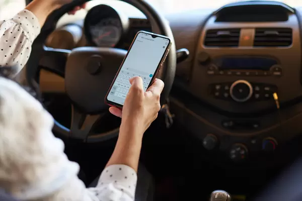 Businesswoman sending a text while driving