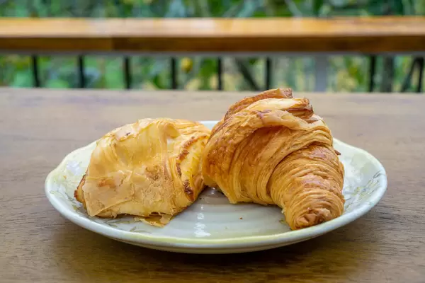 Buttercroissant und Blätterteig-Tasche auf einem weißen Teller Nahaufnahme