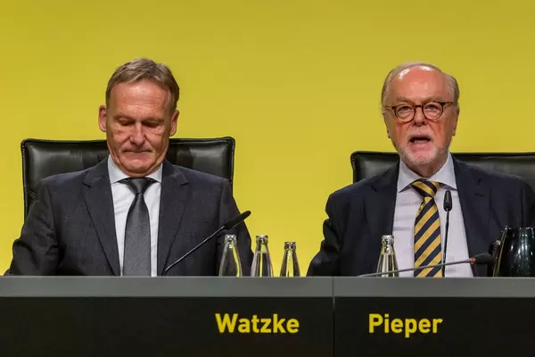 BVB-Chef Hans-Joachim Watzke und Gerd Pieper sitzen hinterm Pult mit Mikro auf der BVB-Hauptversammlung in Dortmund