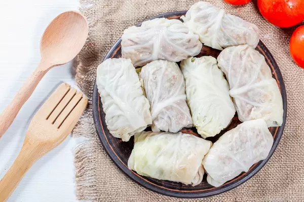 Cabbage rolls with meat and rice on burlap with wooden spoon and fork