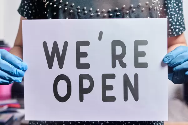 Cafe or restaurant worker hanging a paper with text - we are open. Concept of re-opening public places after covid-19 pandemic