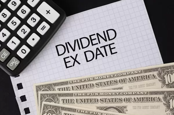 Calculator, money and Dividend Ex Date text on black table
