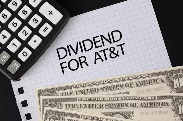 Calculator, money and Dividend For AT&T text on black table