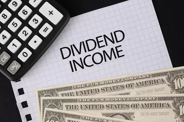 Calculator, money and Dividend Income text on black table