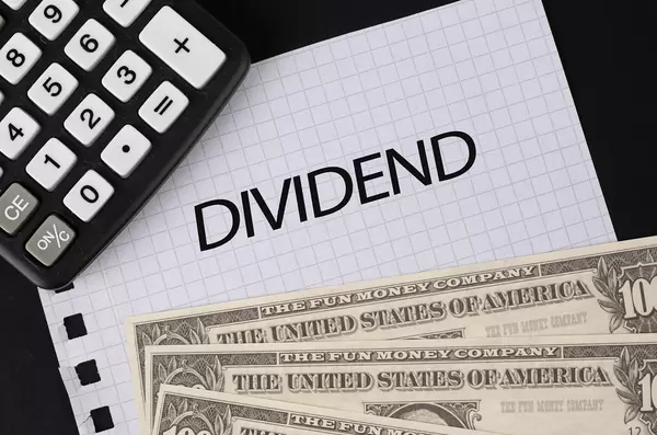 Calculator, money and Dividend text on black table