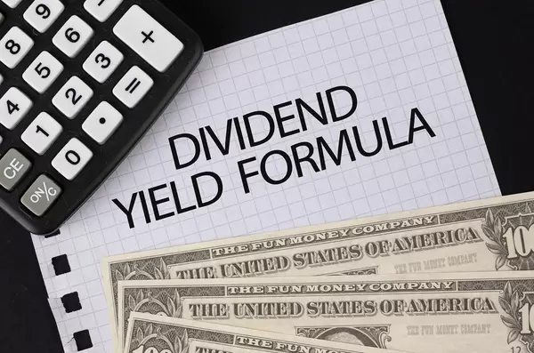 Calculator, money and Dividend Yield Formula text on black table