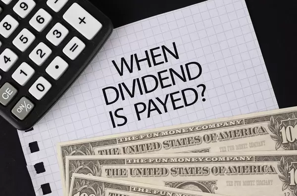 Calculator, money and When Dividend is Payed text on black table