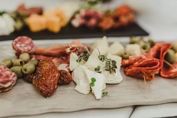 Camambertkäse, Salami, Oliven und getrocknete Tomaten auf einem Holzbrett in Nahaufnahme