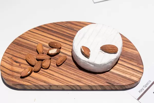 Camembert Weichkäse mit geschälten, ganzen Mandeln auf Holzbrett