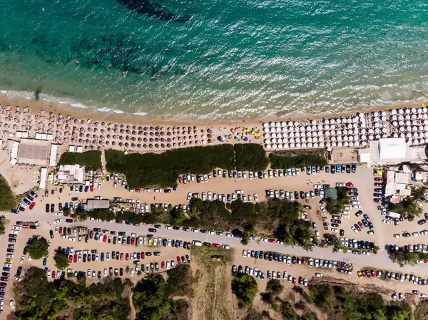 Camping site with cars and beach with parasols. Photographed from above