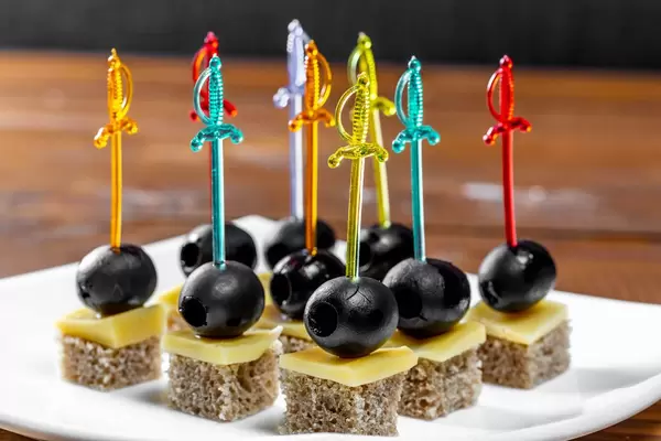 Canape mit Schwarzbrotkäse und -oliven auf einer weißen Platte