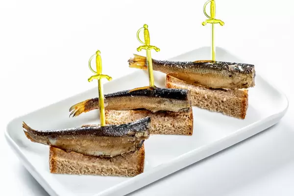 Canape with with smoked sprats and brown bread on plate
