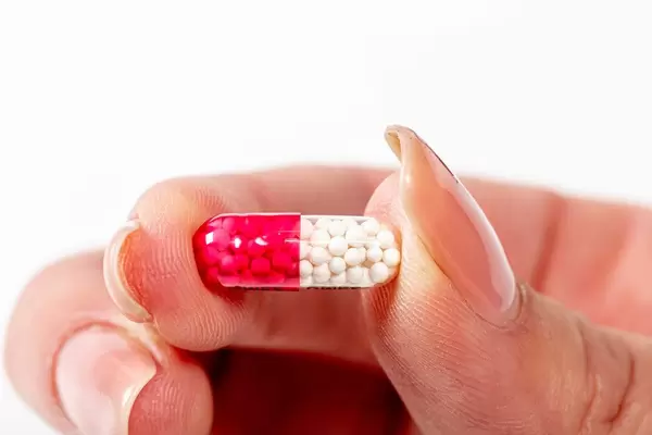 Capsule with white medical granules in female hand (Flip 2019)