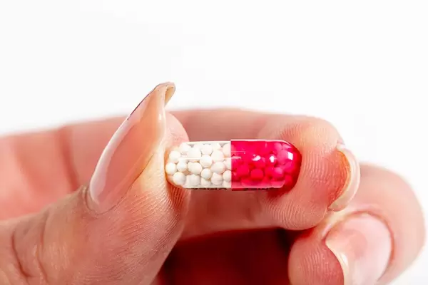 Capsule with white medical granules in female hand