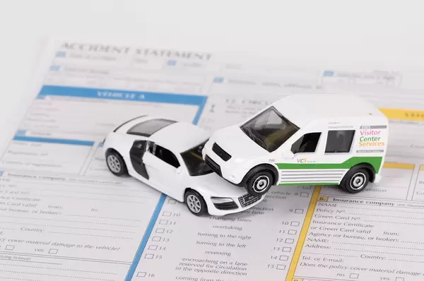 Car insurance report following an accident concept with toy cars on accident statement
