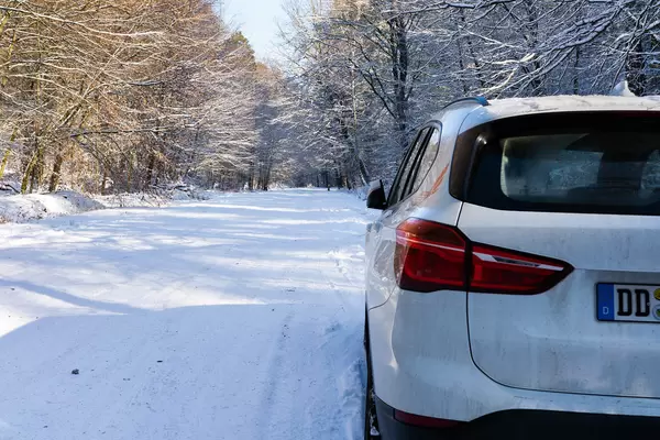 Car-sharing car parked to the side of the snowy forrest road