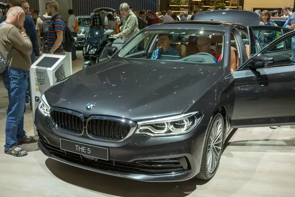 Car show visitors testing the plug-in hybrid vehicle of BMW 5 series 530e xDrive with with all-wheel drive