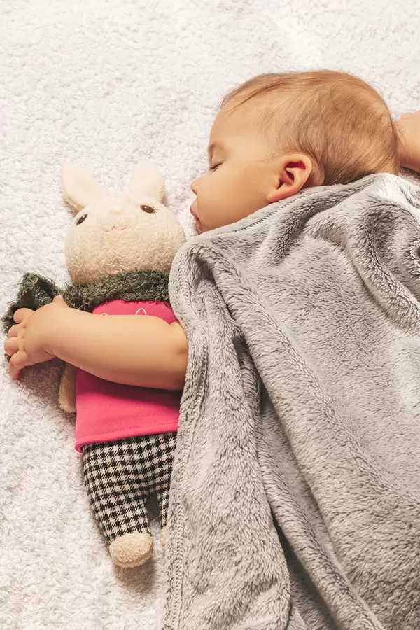 Carefree sleep little baby with a soft toy on the bed