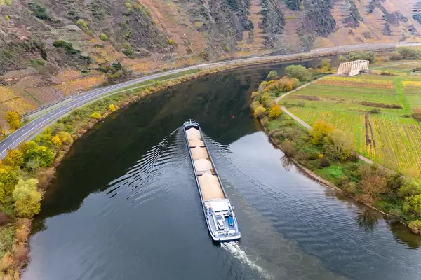 Cargo Ship Loaded with Sand on River Moselle along Highway B49 towards Historical Landmark Kloster Ruine Stuben in Bremm, Germany
