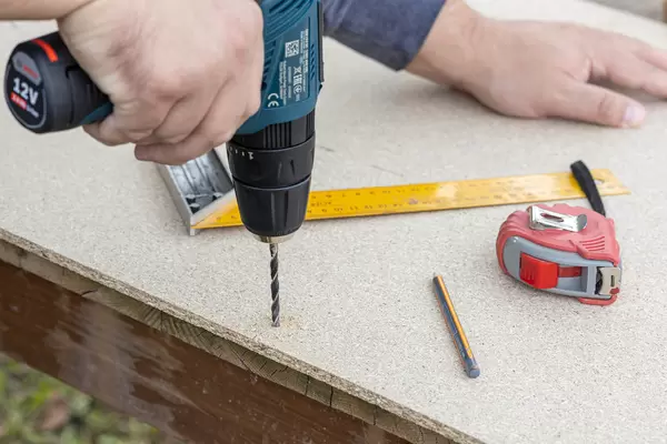 Carpenter drilling a hole in the Plywood
