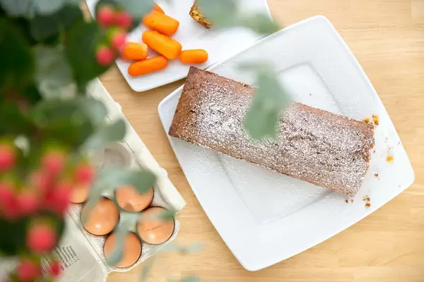 Carrot cake, carrots and eggs with flowers in the foreground