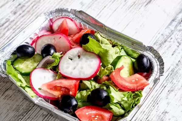Carry out container with dieting green salad with onion and black olives