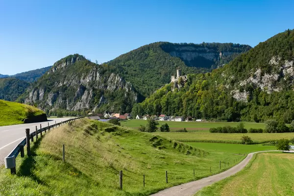 Castle on top of the hill in Swiss countryside next to the road