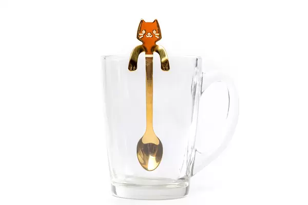 Cat-shaped teaspoon in an empty glass cup