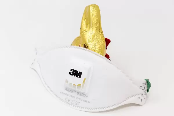 Celebrating Easter in times of Corona: 3M Aura 9332+ FFP3 disposable respirator and a chocolate easter bunny with white background