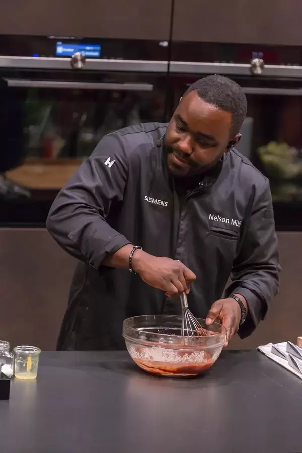 Celebrity chef Nelson Müller stirring a sauce with an eggbeater