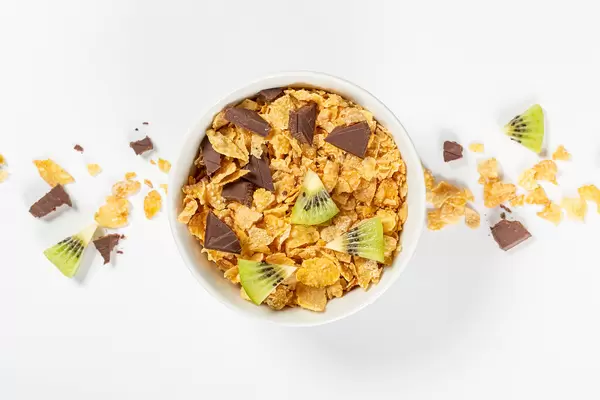 Ceramic bowl of corn flakes with kiwi and chocolate, top view