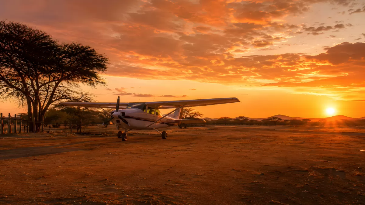 Cessna-Kleinflugzeug bei Sonnenuntergang in der Savanne