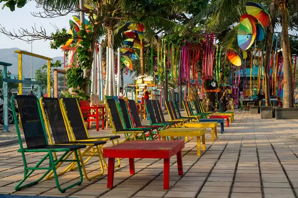 Chairs and Tables in different Colors at a popular Beach Bar with Palm Trees and Decorations at My Khe Beach in Da Nang, Vietnam