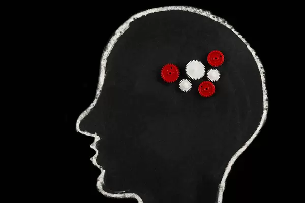 Chalk-drawn silhouette of a human head with gears on a black background, human brain concept
