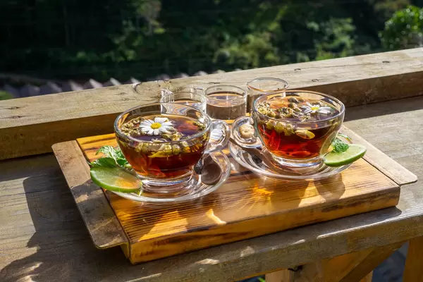 Chamomile Tea in Glass Cups on Glass Saucers with Daisy Flowers, Limes, Mint, Honey and Syrup on a Wooden Tray in a Cafe in Da Lat, Vietnam