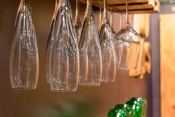 Champagnergläser und Weingläser hängen kopfüber an Holzbrett vor dunkler Wand