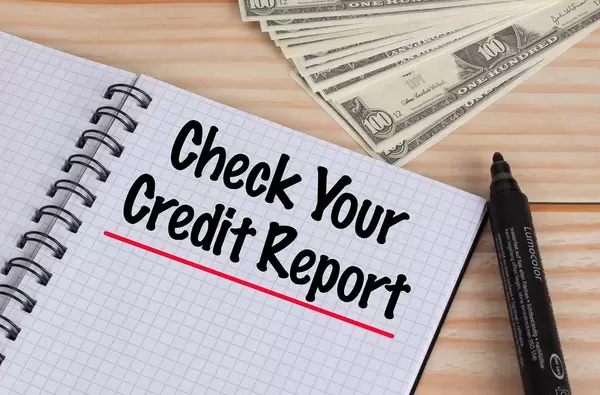 Check Your Credit Report text in notebook and Dollar banknotes on wooden table