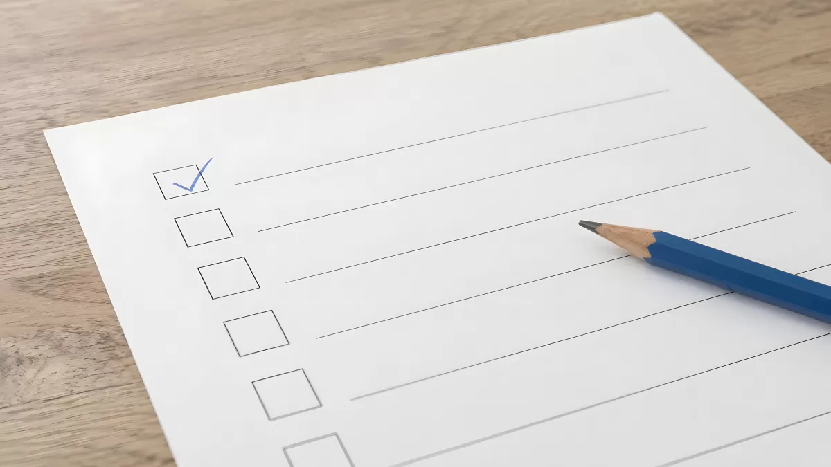 Checkliste mit Häkchen und blauem Bleistift auf Holztisch