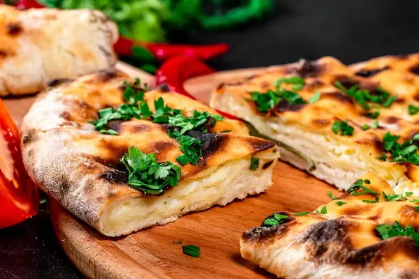 Cheese khachapuri sliced with parsley on the kitchen Board