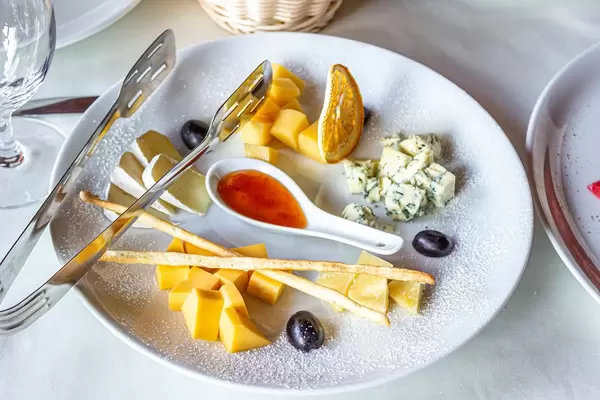 Cheese plate: hard cheese, Camembert cheese, Dor blue, bread sticks, honey and grapes on plate