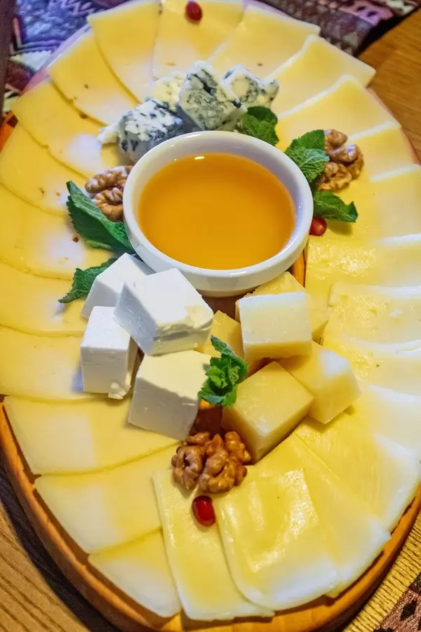 Cheese slices of different types with honey, mint leaves and walnuts