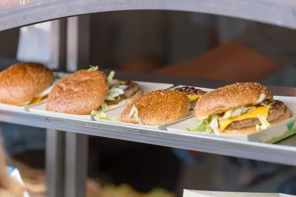 Cheeseburgers being prepared and put to economy-friendly paper plates at Tomorrowland festival